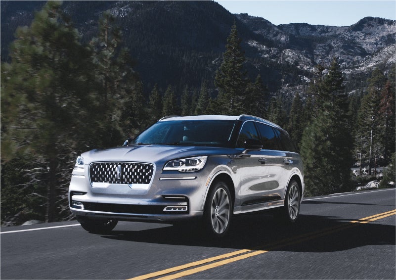 A 2023 Lincoln Aviator® Grand Touring SUV being driven on a winding road to demonstrate the capabilities of all-wheel drive | Cogswell Lincoln in Russellville AR